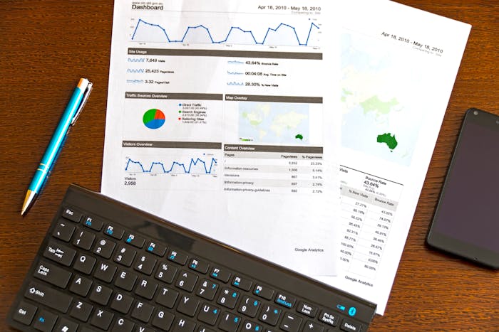 Flatlay of business analytics report with keyboard and smartphone on wooden desk
