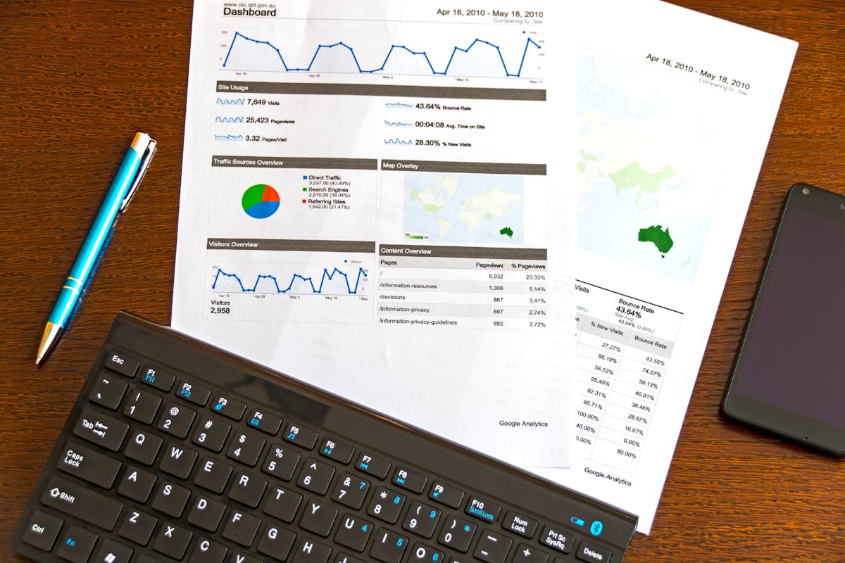 Business analytics flatlay showing report documents with keyboard and smartphone on wooden desk